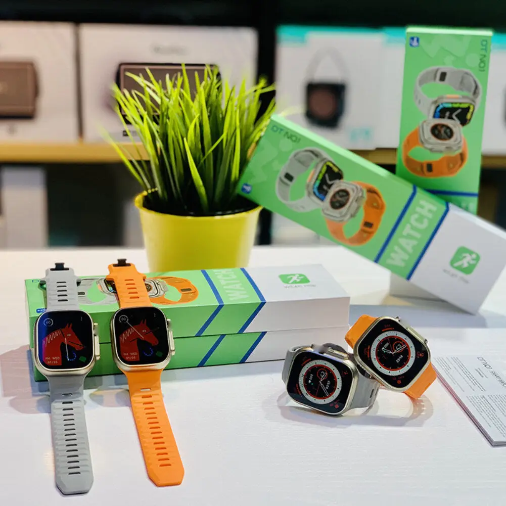 ساعت هوشمند دی تی نامبر وان مدل DT8Ultra 49mm با جعبه سبز رنگ و دو بند نقره ای و نارنجی در کنار گلدان